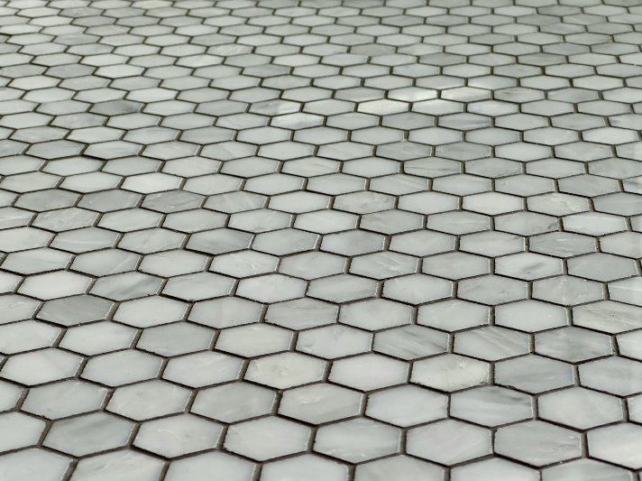Patterned luxury vinyl tile floors draw the eye across a large kitchen with dark cabinets and marble countertops.